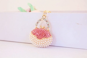 Close-up of golden handbag keychain with pink rhinestones and white pearls detail