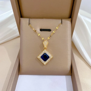 Elegant gold necklace with a square blue gemstone pendant in a beige jewelry box