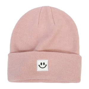 Close-up of pink knitted beanie featuring a white square patch with a black smiley face