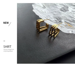 Detailed view of layered geometric gold square earrings on textured dark background