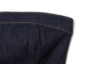 Gros plan détaillé du tissu denim bleu foncé montrant les coutures précises et la texture