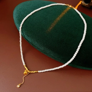 Detail of gold pearl necklace with zircon heart pendant on green velvet display