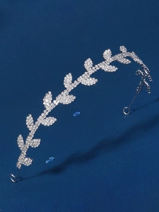 Detailed view of silver leaf-shaped headband with sparkling rhinestones on blue fabric