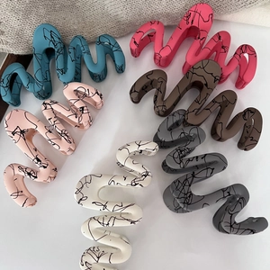 Artistic wave hair claws in matte colors with black ink splatters on white background