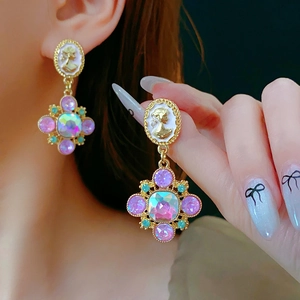 Close-up of vintage baroque style earrings with floral crystal inlays and white relief