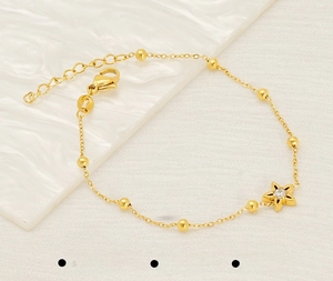 Detailed shot of gold titanium steel bracelet with flower charm and cubic zirconia inlay