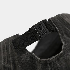 Detail of adjustable black buckle and durable nylon strap on washed gray baseball cap