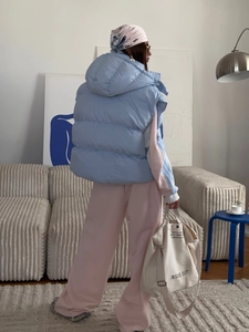 Back view of a light blue hooded puffer vest paired with a pink tracksuit set