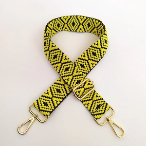 Close-up of yellow and black geometric jacquard bag strap with gold metal buckles