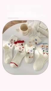 Vue détaillée de chaussettes blanches avec motifs de Petit Chaperon Rouge et pommes