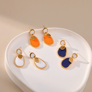 Detail of three pairs of vintage enamel earrings in orange, white and dark blue finishes