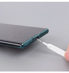 Detail of a small brush cleaning dust from a mobile phone charging port