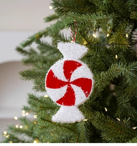 Detail of red and white candy cane ornament hanging on a Christmas tree with warm lights