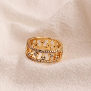Detailed shot of gold-plated hollow geometric ring with cubic zirconia on linen fabric