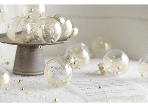 Detail of a clear Christmas ornament filled with elegant gold ribbon and pearl chains