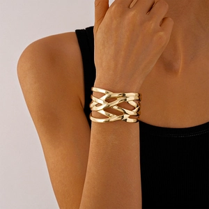 Macro shot of a chunky gold multilayer woven cuff bracelet on a model wrist