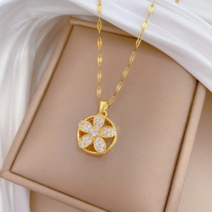 Close-up of golden rotating flower pendant necklace with shimmering crystals on silk fabric