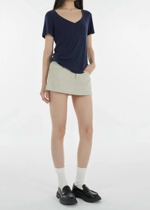 Detailed look at navy V-neck t-shirt with beige mini skirt and chunky loafers