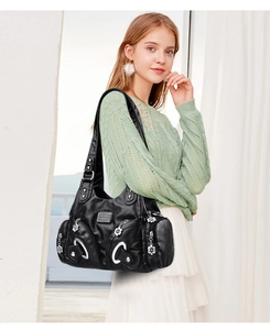 Detail view of black PU leather tote bag with silver flower zippers on a female model