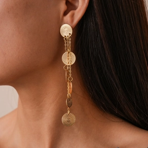 Detailed view of long tiered tassel earrings with textured gold circles on model