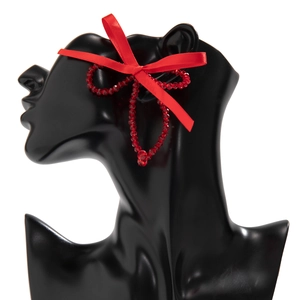 Detail of red beaded hoop earrings with satin ribbon bow on a black mannequin
