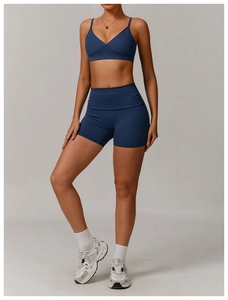 Detail of navy blue V-neck sports bra and high-waisted seamless fitness shorts on model