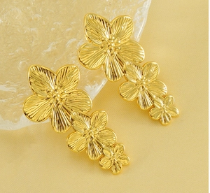 Detail of gold floral earrings with triple blossoms and fine radial texture on silk