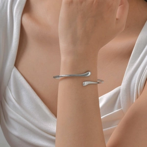 Close-up of minimalist silver stainless steel open bangle worn on a woman's wrist