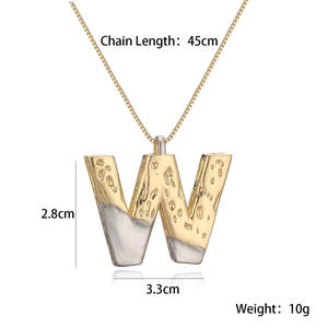 Macro detail of two-tone gold and silver lava texture letter W pendant necklace