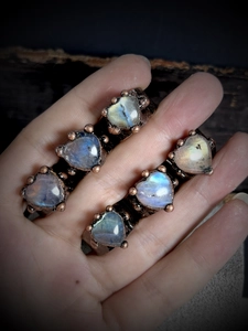Handmade copper rings set with heart-shaped moonstones showing blue iridescent glow
