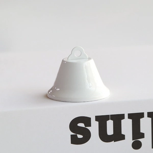 Close-up of a glossy white lacquered metal bell ornament with top hanging loop