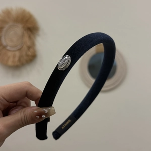 Detail of dark blue velvet headband with silver oval logo plaque and inner woven label