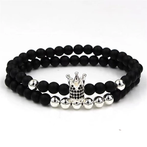 Close-up of double-layer bracelet with black matte beads and silver crown charm