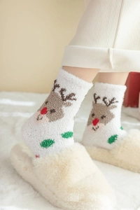 Détail des chaussettes en molleton corail blanc avec motifs de rennes pour la chaleur d'hiver