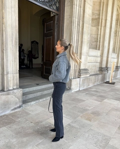 Outdoor street style shot of a grey tweed cropped coat with black straight jeans and boots