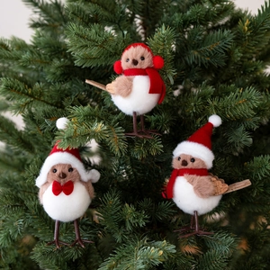 Three Christmas bird ornaments with red hats and scarves on pine branches