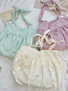 Three pleated canvas tote bags in green, pink and white with adjustable ribbon handles