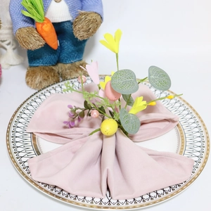 Detail of Easter napkin ring with faux eggs and yellow flowers on a white plate