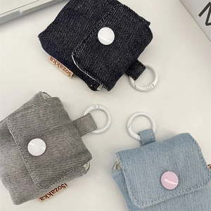 Detailed view of denim headphone cases in blue and grey with snap buttons and hooks