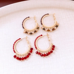 Detail of handmade hoop earrings with woven cotton thread and faceted crystal beads