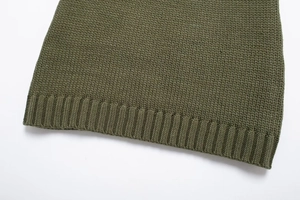 Dettaglio macro dell'orlo a costine e della trama di un maglione verde lavorato a maglia