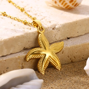 Detailed close-up of a gold starfish pendant necklace on a sandy beach background