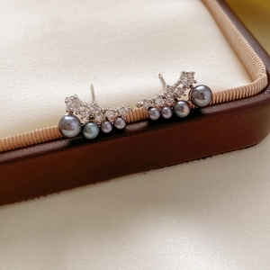 Close-up of 18k gold plated silver earrings with gradient grey pearls and zircon inlay
