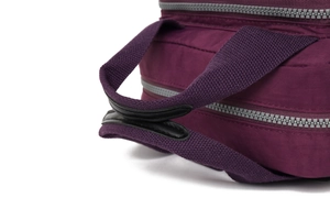 Détail du sac à langer en nylon violet montrant les poignées en cuir et les fermetures