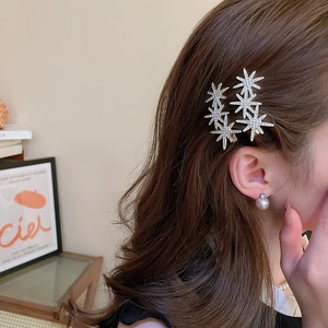 Close-up of sparkling rhinestone star hair clips and pearl earrings worn by a model