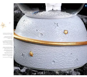 Macro detail of moon-textured music box base with golden stars and astronaut figurine