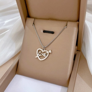 Détail du pendentif cœur fléché argenté avec gravure Love dans un écrin beige