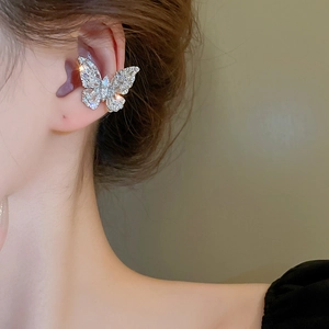 Macro shot of a silver butterfly ear cuff with sparkling zircon stones on female ear