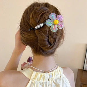 Détail de la pince à cheveux fleur tissée avec strass en cœur sur une pince bec de canard noire
