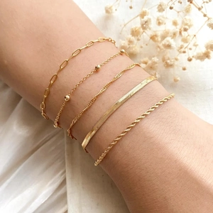 Close-up of five layered gold-plated bohemian chain bracelets on a model wrist